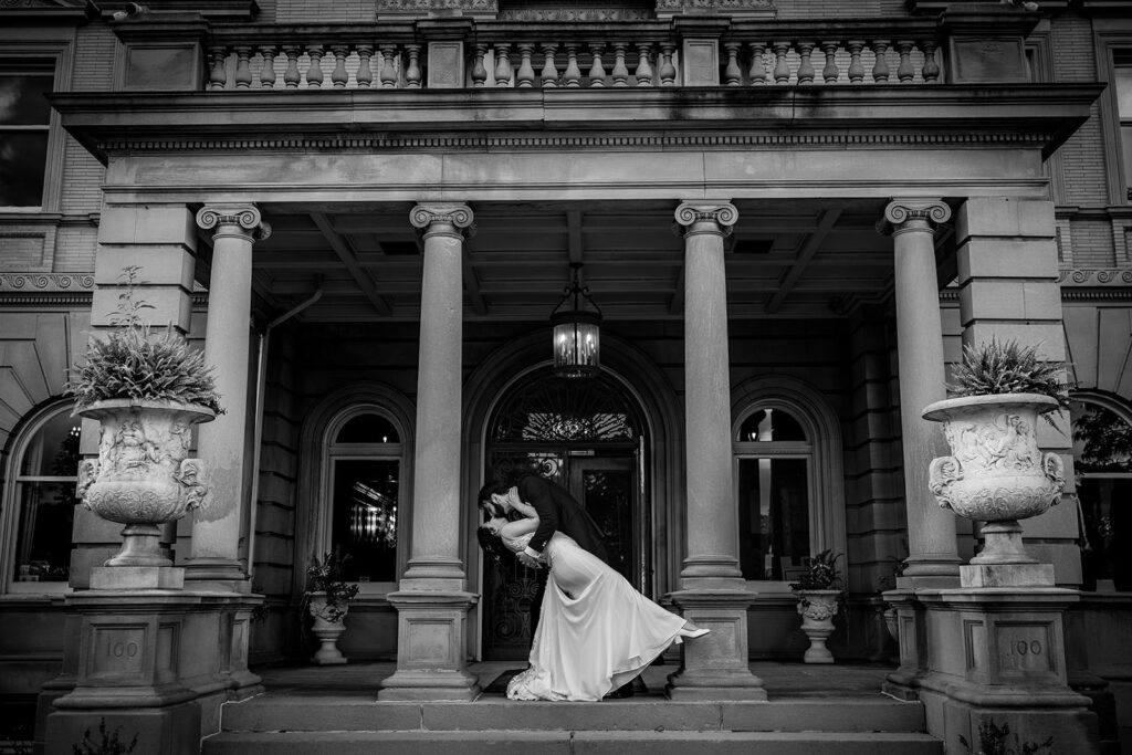 black and white photo of the couple kissing at the front of semple mansion