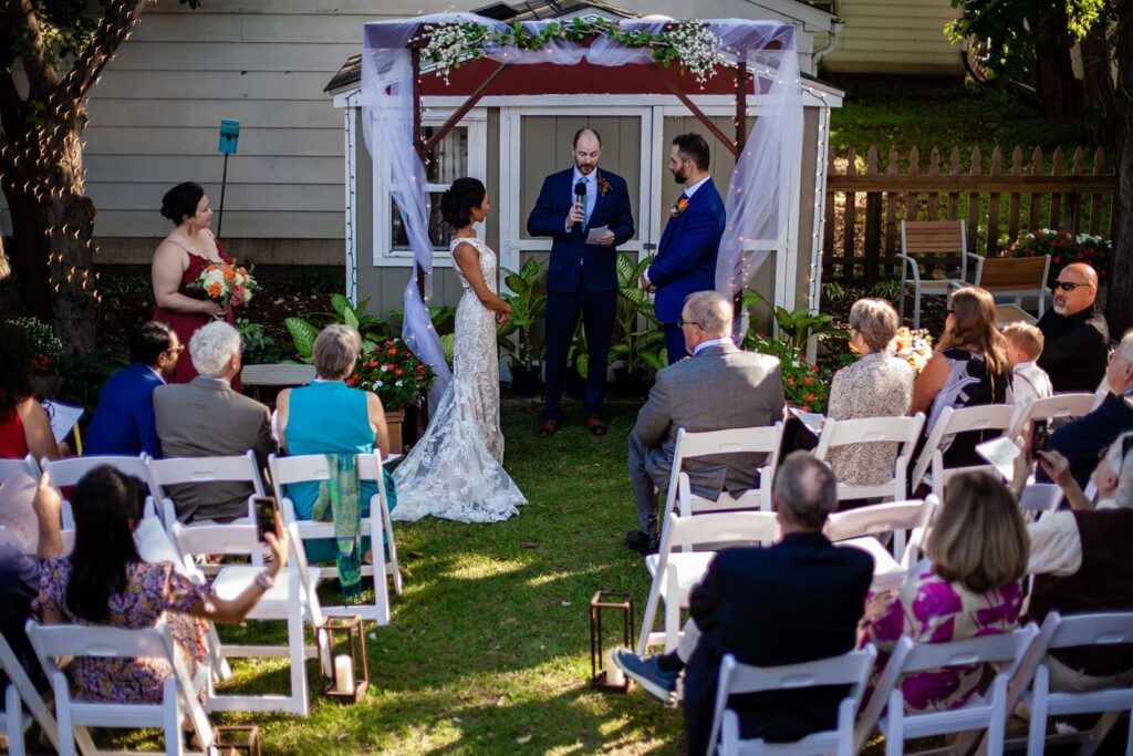 guests seated on wooden chairs during the ceremony during st paul backyard wedding