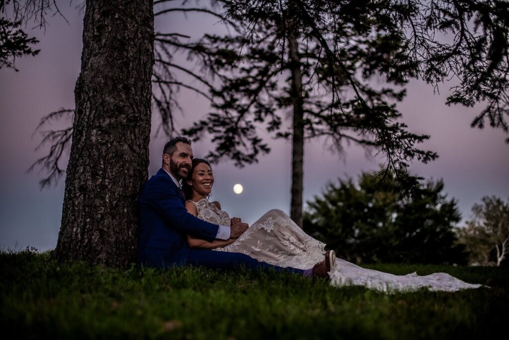 nighttime photo of bride and groom with the moon in the backdrop