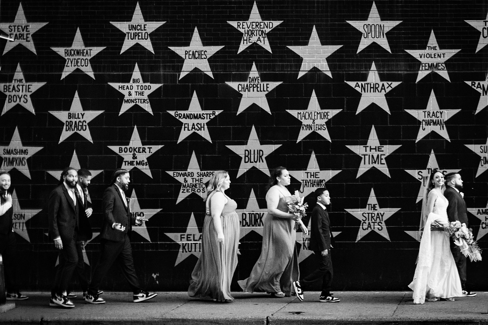 motion photograph of wedding party walking past iconic mural wall in minneapolis