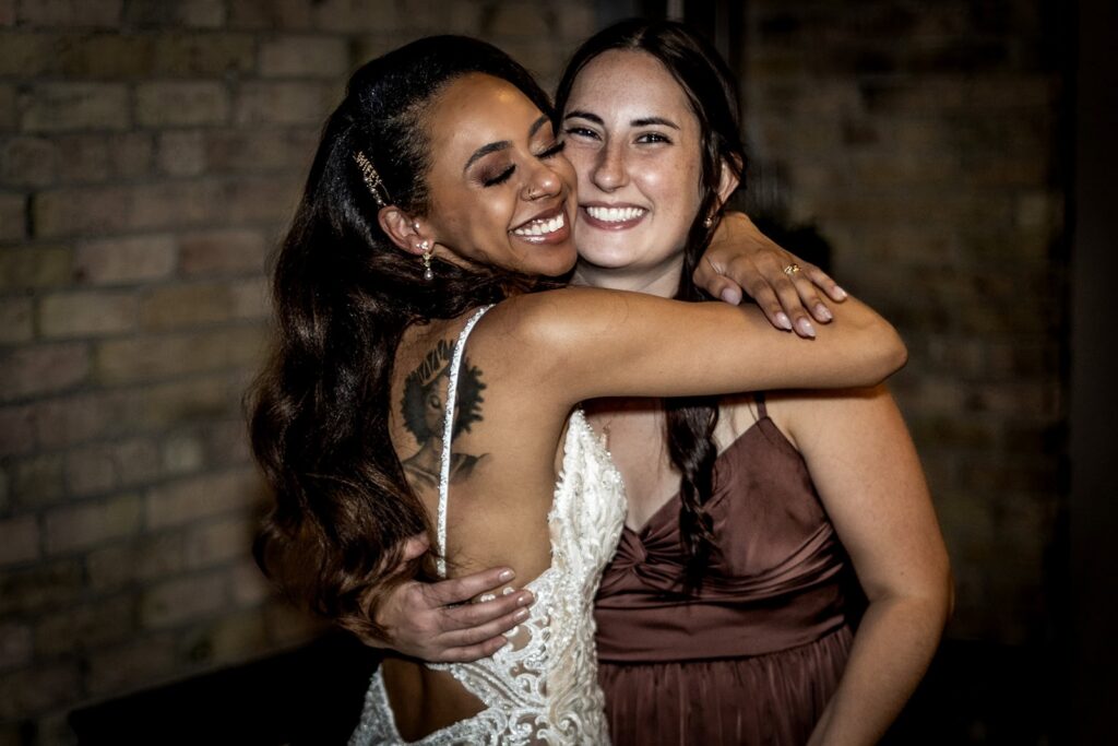 Candid photo of bride hugging bridesmaid during Minneapolis wedding reception.