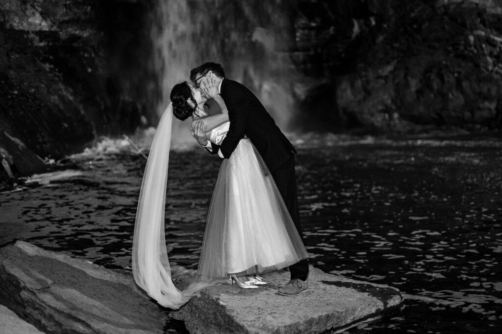 black and white photo of bride and groom kissing at Minnehaha Falls