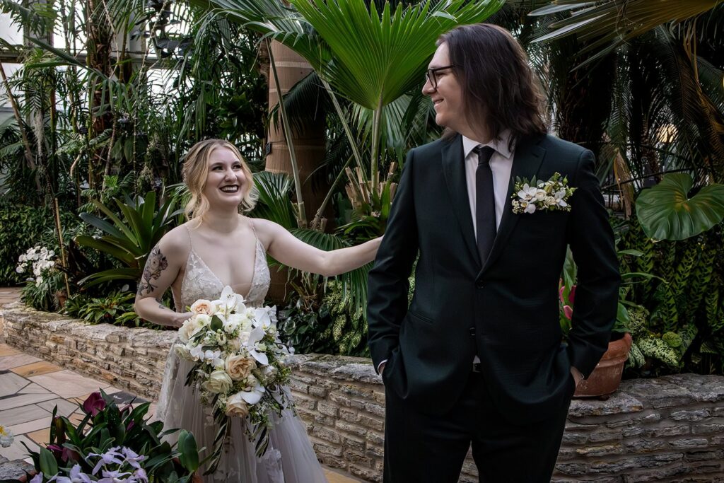 Groom turning to see his bride during a first look in the glass conservatory at Como Park