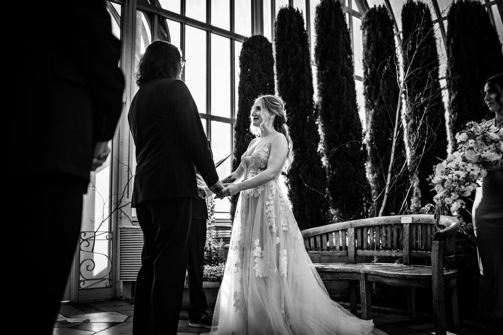 Couple exchanging vows beneath the glass ceiling of Como Park Conservatory in St. Paul