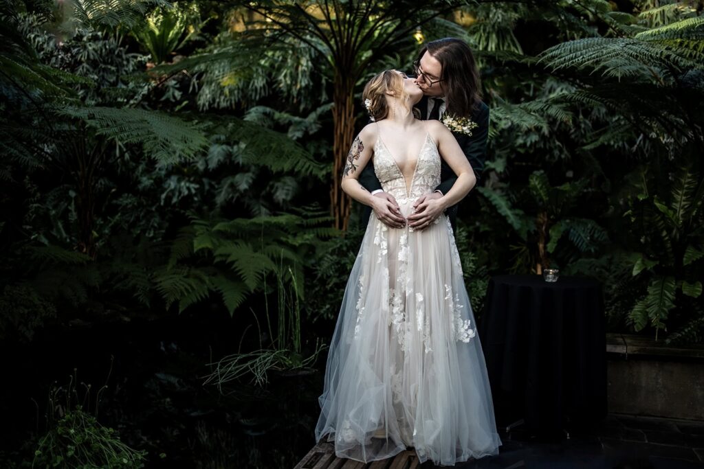 Bride and groom portraits inside Como Zoo Conservatory surrounded by tropical plants in St. Paul