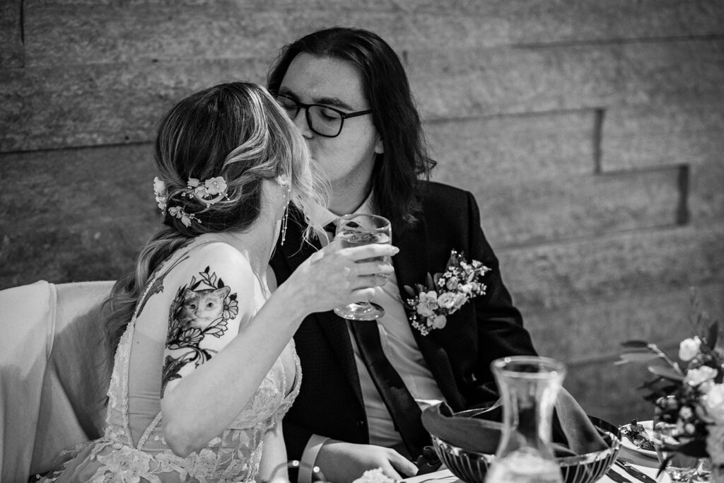 black and white photo of bride and groom kissing during wedding reception