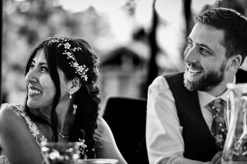 Bride and groom listening to wedding speeches at their summer reception in minnesota