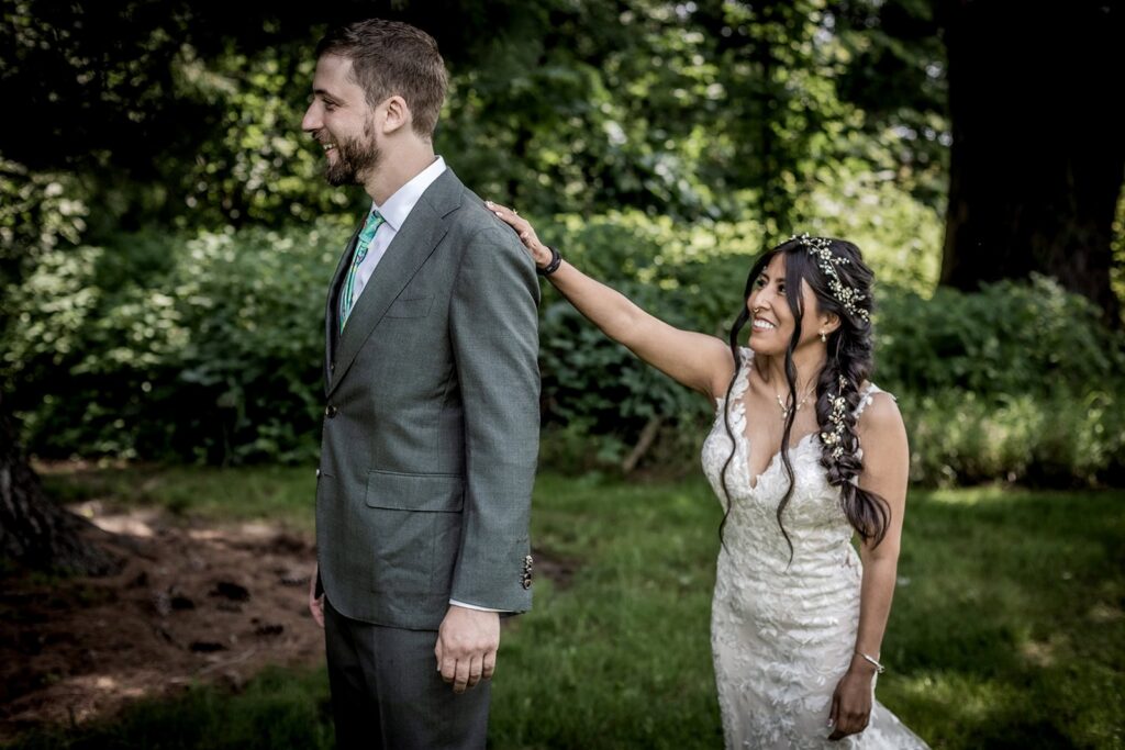 Emotional first look moment between bride and groom surrounded by summer greenery